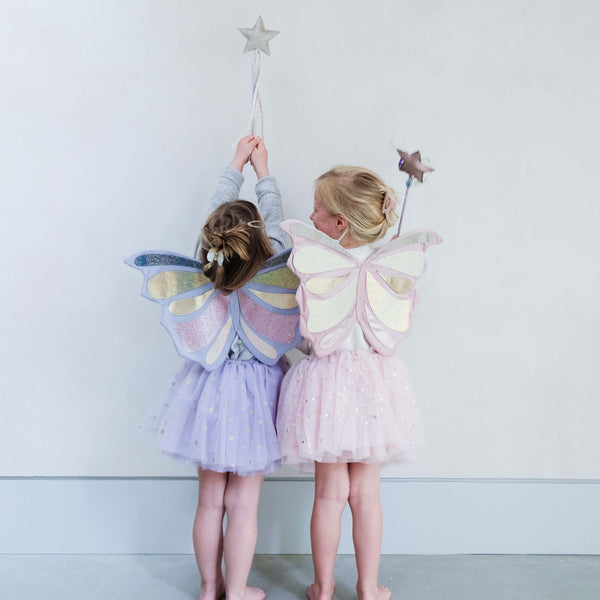 Two young children wearing Mimi & Lula Emmelina Fairy Wings in pink and pastel blue, holding star wands and wearing matching tutus.